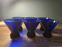 Front view of all six cobalt blue stemless martini glasses on table