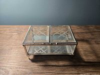 Closed rectangular glass jewellery box showing etched lid and beaded metal frame