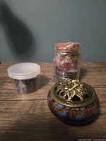Incense burner with lid next to three packs of incense coils