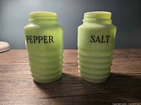 Front view of both jadeite glass shakers showing PEPPER and SALT labels