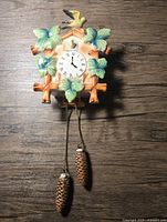 Full view of ceramic cuckoo clock wall pocket with hanging pinecone weights