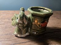 Front view showing elephant figure and floral relief on planter