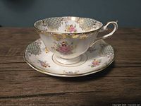 Teacup on saucer profile view showing pattern and gold trim