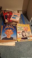 Stacks showing Superman comic, Charlie Brown paperback, and numerous MAD magazines