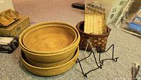 Grouped view of nested baskets, brown basket with trays, metal easels, brass dishes