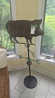 Full view of brass pig weathervane on stand showing pig figure, directional arms, arrow, and base