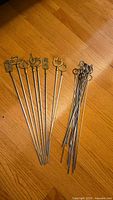 Group of brass top skewers and plain metal skewers on floor