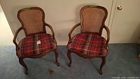 Two matching wood cane armchairs with red plaid cushions