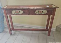 Front view of hand-painted console table showing two drawers with floral designs and overall style