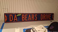 Front view of entire "DA BEARS DRIVE" metal sign on counter