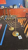 Two brass menorahs on table showing overall form and matching design