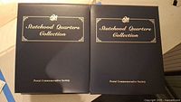 Front view of both navy blue slip-case binders showing titles