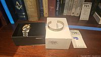 Watch in Seiko box beside white outer box and POW bracelet packaging