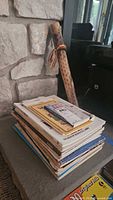 Stack of sheet music with rain stick against stone wall