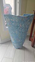 Full view of tall blue textured pottery vase with abstract pattern