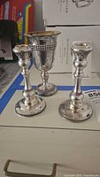 Pair of candlesticks and Kiddush cup grouped on tabletop