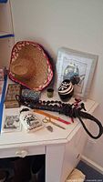 Full lot on desk including sombrero, necklace, whip, boxes, scissors, chopsticks, vase, framed bird art, arrow, shot glass partially visible