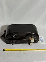 Front view showing speaker grille, tuning dial, knobs, tape measure for scale