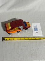 Side view of Rodimus Prime in vehicle mode next to tape measure showing length