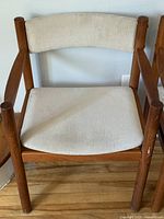 Front view of first teak armchair showing frame and upholstery