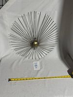 Full view of starburst sculpture with measuring tape showing diameter