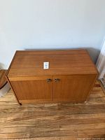 Front view of teak media cabinet showing double doors and metal pulls