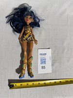Full view of doll beside ruler showing length