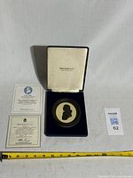 Medallion inside open presentation case with certificate documents displayed