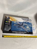 Front of sealed Revell Top Gun Maverick F/A-18E Super Hornet model kit box with measuring tape for scale