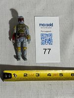 Full view of figure beside tape measure showing roughly 3.75-inch height