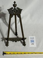 Front view of brass easel showing ornate details and measuring tape indicating height