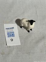 Front view of ceramic lamb figurine beside lot tag