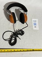 Headphones full view with coiled cable and tape measure for scale
