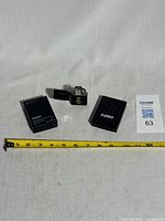 Lighter open with both parts of original box beside measuring tape