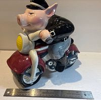 Side view of ceramic biker pig cookie jar with ruler for scale