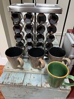 Full view of chrome spice rack holding 20 bottles and four mugs in front
