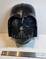 Front view of Darth Vader talking mask with ruler for scale