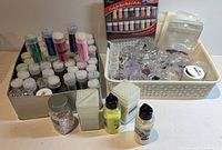 Overview of metal tin and basket containing assorted glitter vials, jars, squeeze bottles and boxed set