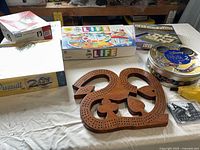 Assorted board games including Game of Life, Disney Trivia 2 tin, Upwords, Trivial Pursuit 20th, wooden cribbage board on table