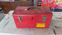 Exterior view of red metal toolbox, top, handle and latches visible