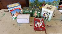 Overview showing four boxed Christmas village pieces, plain white box and red cards box