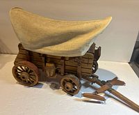 Right side view of wooden covered wagon with canvas cover and hitch