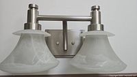 Front view of brushed nickel double sconce with frosted glass shades