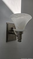 Side angle of brushed nickel wall sconce mounted on wall