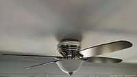 Side view of installed Hunter ceiling fan showing chrome housing, frosted glass light bowl, portion of blades