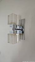 Front angle of wall sconce showing chrome backplate and two cube glass shades