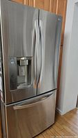 Front view of closed refrigerator showing stainless finish and dispenser