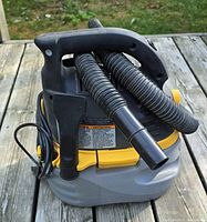 Front view showing handle, hose wrapped around canister and crevice tool attachment