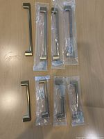 Eight brushed gold cabinet pulls, some packaged