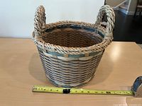 Round straw basket with rope handles and teal accents, tape measure shows size